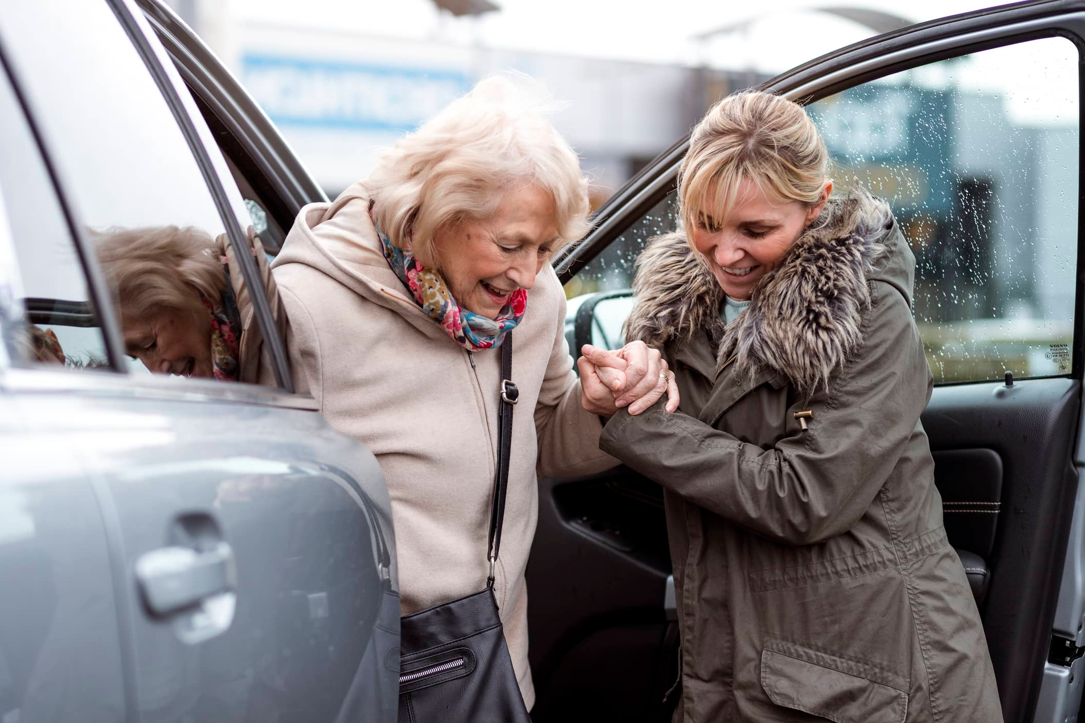 Caregiver helps client get out of the passenger seat of a car